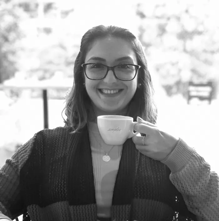 Lívia sorrindo com uma xícara da Simples na mão.